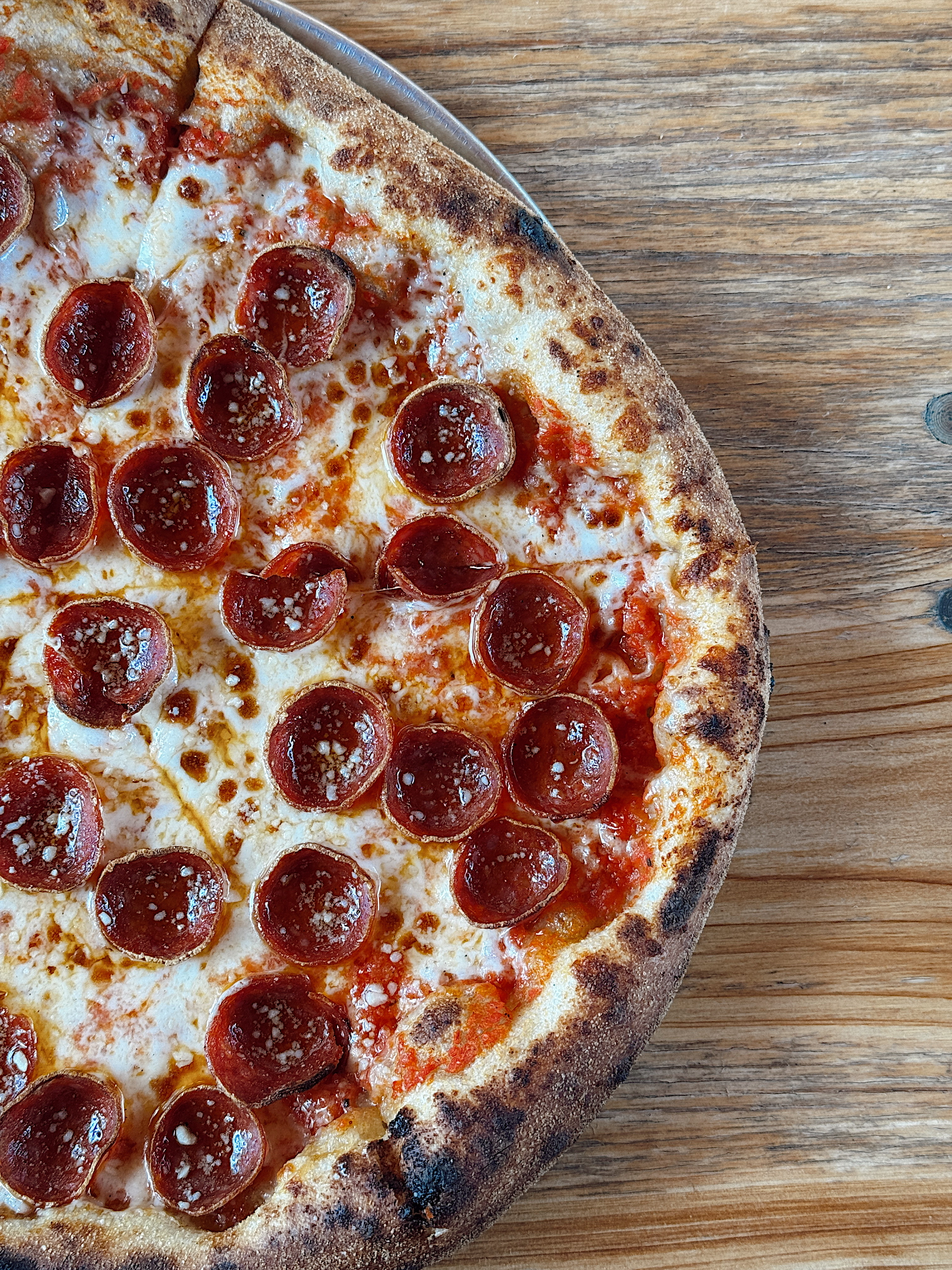Wood-fired pepperoni pizza with a charred, blistered crust made by Pizzeria Coco