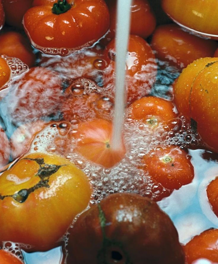 Fresh red and yellow tomatoes rinsed under water for Pizzeria Coco pizza sauce